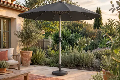 Parasol rond Kingsleeve anthracite ouvert dans un jardin, avec mât en aluminium et manivelle intégrée.