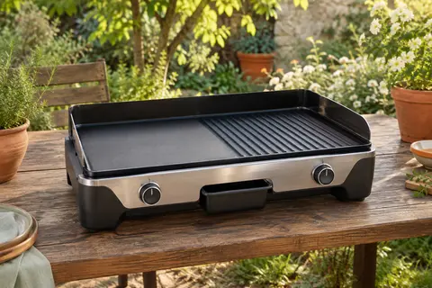 Plancha électrique argent et noire avec plaques réversibles et pare-éclaboussures sur une terrasse de jardin.