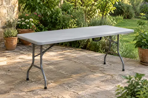 Table pliante rectangulaire gris clair dans un jardin, avec plateau épais et pieds pliants en acier