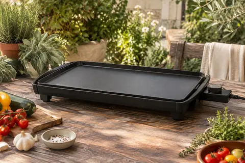 Plancha électrique noire Tefal Malaga XL posée sur une table en bois dans un jardin