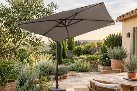 Parasol rectangulaire gris incliné dans un jardin, avec structure en acier anthracite et toile polyester.