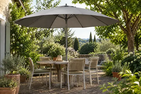 Parasol rond gris à toile inclinable installé au-dessus d’un espace repas dans un jardin.